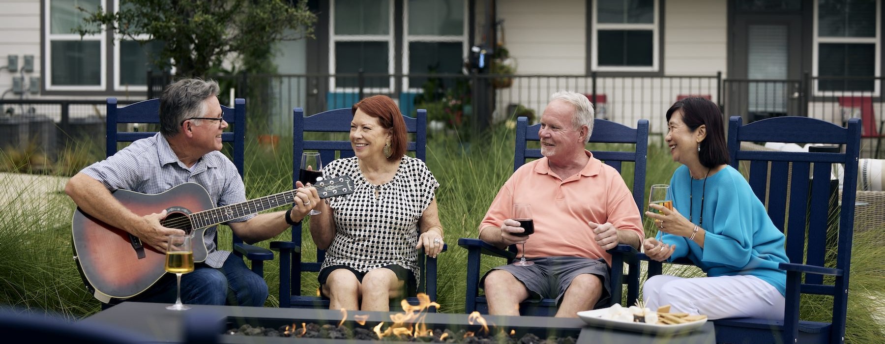 The lifestyle you've been waiting for. people sitting around fire and a man playing a guitar